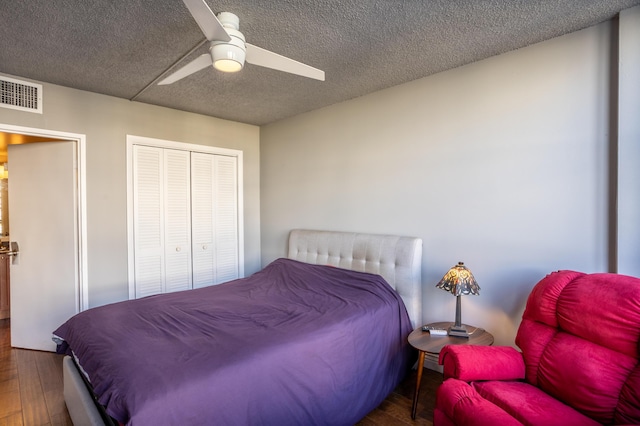 bedroom featuring ceiling fan, wood-type flooring, a closet, and a textured ceiling