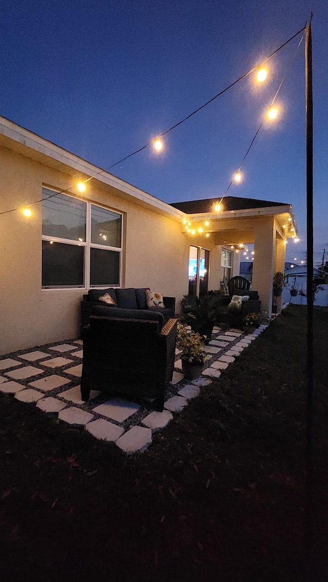 back house at twilight with outdoor lounge area and a patio area