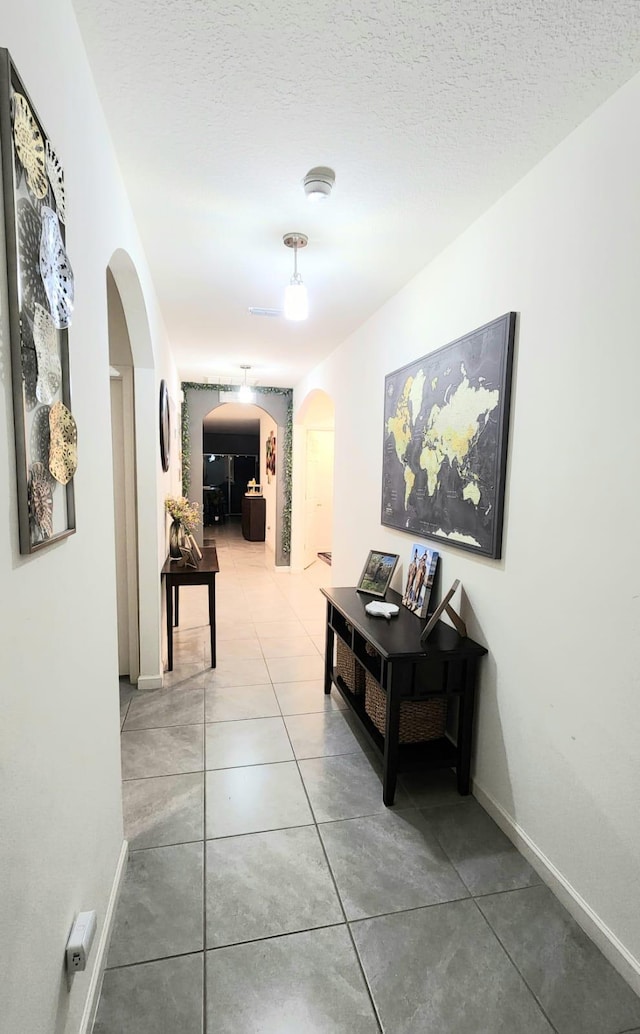 hallway with tile patterned flooring and a textured ceiling