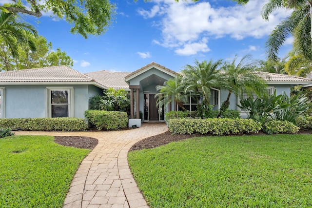 view of front of property with a front yard, a tiled roof, and stucco siding