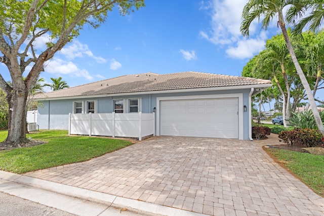 ranch-style house with stucco siding, a tile roof, an attached garage, decorative driveway, and a front yard