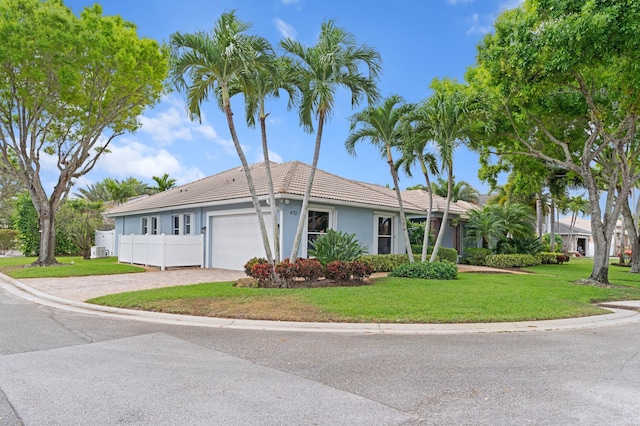 ranch-style home featuring a garage, a tiled roof, fence, decorative driveway, and a front yard