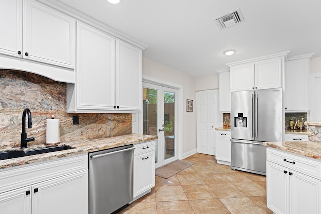 812 NW 26th St, Wilton Manors, FL 33311 - kitchen featuring stainless steel appliances, a sink, tasteful backsplash, white cabinetry, and light stone countertops