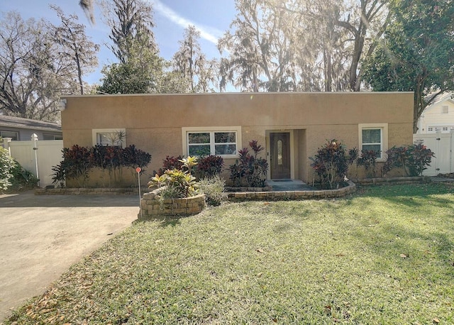 view of front of property with fence, a front lawn, and stucco siding