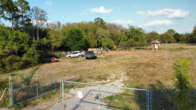 view of yard featuring a gate, a wooded view, and fence