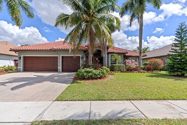 mediterranean / spanish home featuring a garage, a front lawn, decorative driveway, and stucco siding