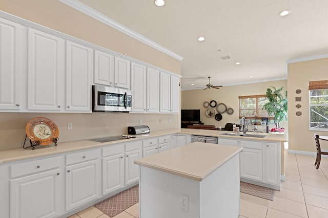 kitchen featuring stainless steel appliances, a peninsula, a sink, a center island, and crown molding