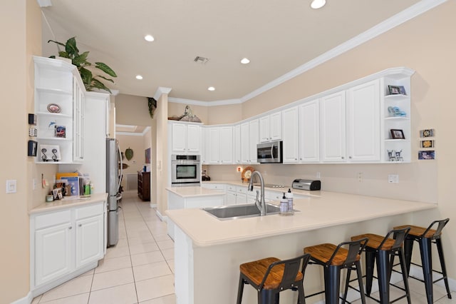 kitchen with a peninsula, stainless steel appliances, a sink, visible vents, and open shelves