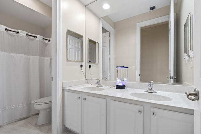 full bath featuring visible vents, double vanity, a sink, and toilet