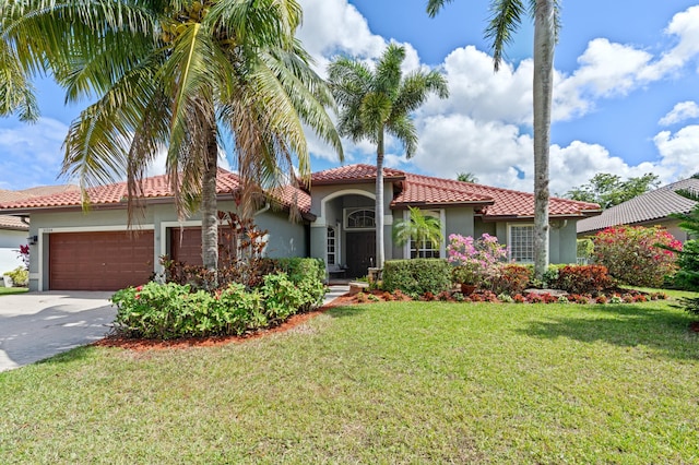 mediterranean / spanish home featuring a garage, concrete driveway, a tiled roof, a front lawn, and stucco siding