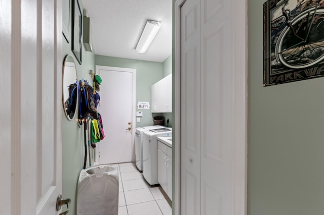 washroom featuring cabinet space, independent washer and dryer, a textured ceiling, and light tile patterned flooring