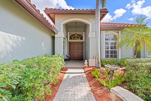 entrance to property featuring a tiled roof and stucco siding