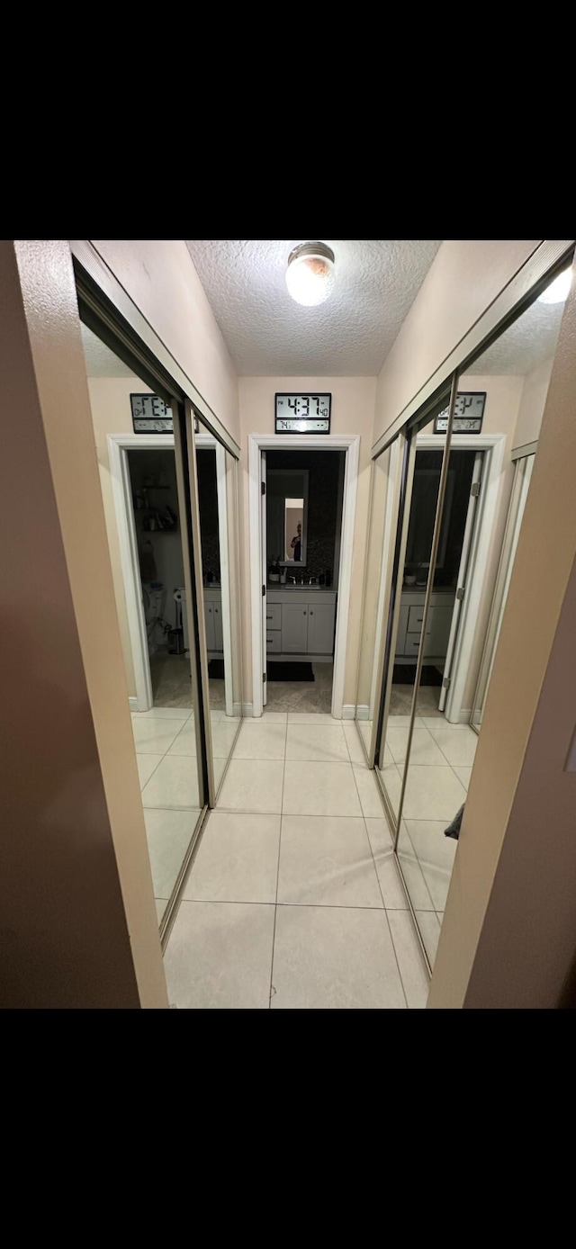 hall with a textured ceiling and light tile patterned floors