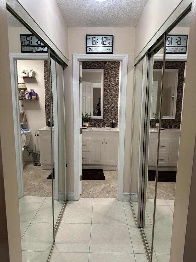 interior space with light tile patterned floors, a textured ceiling, and a sink