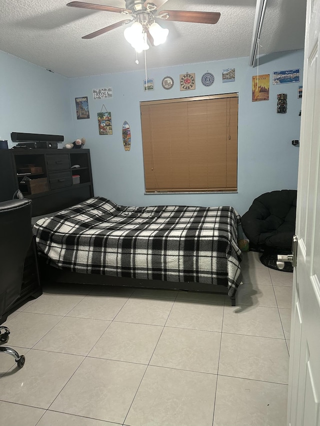 bedroom featuring light tile patterned flooring, ceiling fan, and a textured ceiling