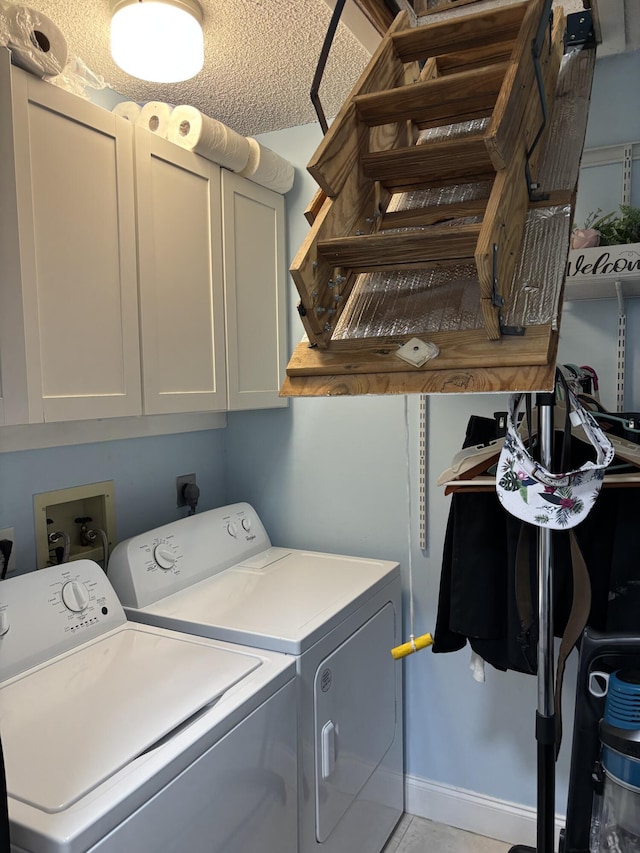 laundry area with a textured ceiling, separate washer and dryer, light tile patterned floors, and cabinet space