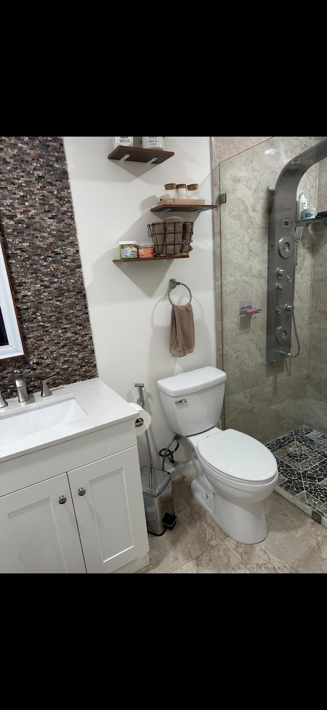 bathroom with vanity, toilet, and a tile shower