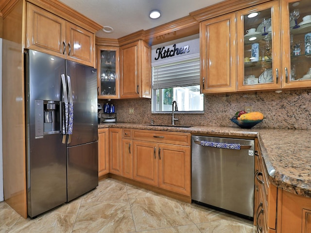 kitchen with light stone counters, stainless steel appliances, sink, and backsplash