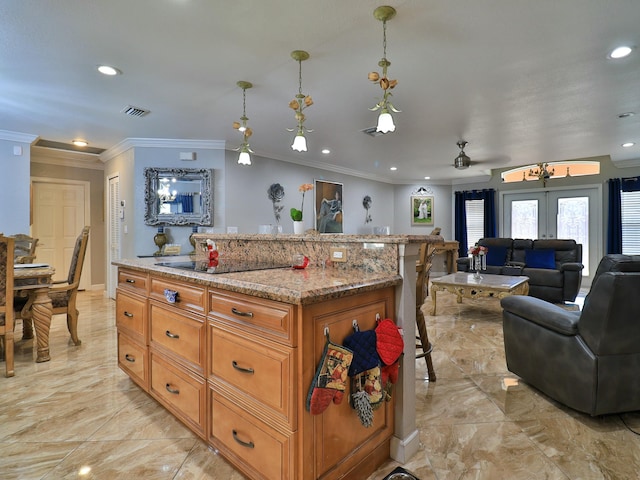 kitchen featuring a kitchen breakfast bar, a center island, light stone counters, black electric cooktop, and decorative light fixtures