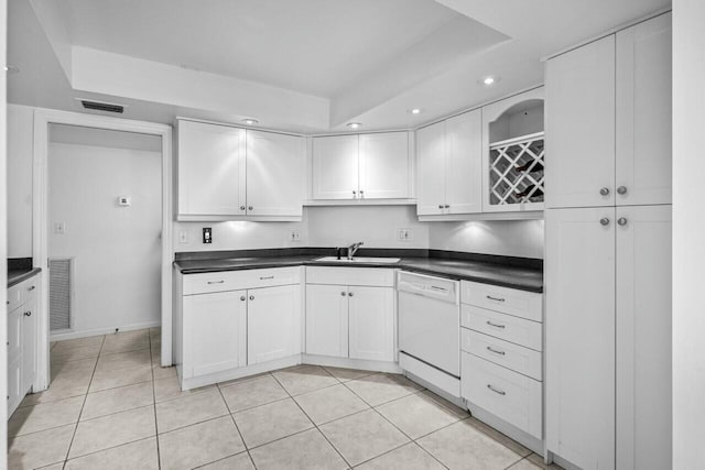 kitchen with light tile patterned flooring, dishwasher, sink, white cabinets, and a tray ceiling