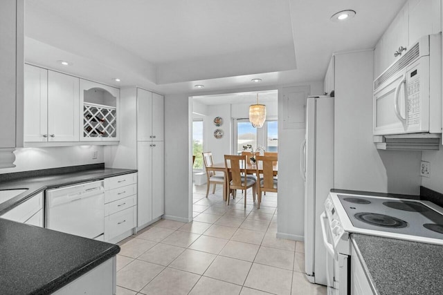 kitchen featuring a raised ceiling, white cabinets, white appliances, and decorative light fixtures