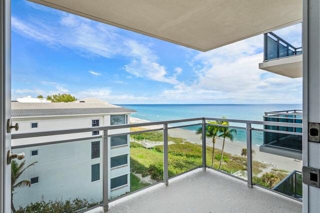 balcony with a water view and a view of the beach