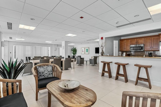 dining space with a drop ceiling and light tile patterned floors