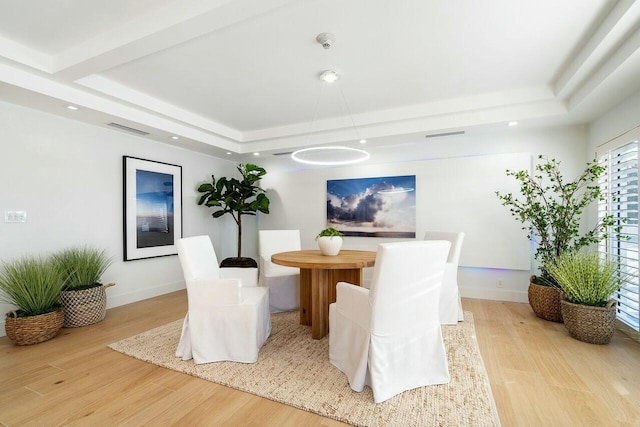 dining room featuring light hardwood / wood-style flooring and a raised ceiling