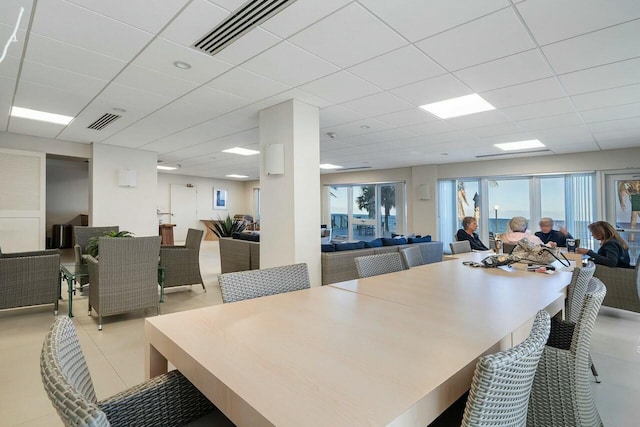 dining area with a paneled ceiling and light tile patterned floors