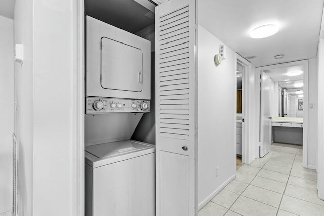 laundry room with stacked washer and clothes dryer and light tile patterned floors