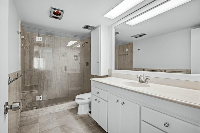 bathroom with vanity, a shower with door, and toilet