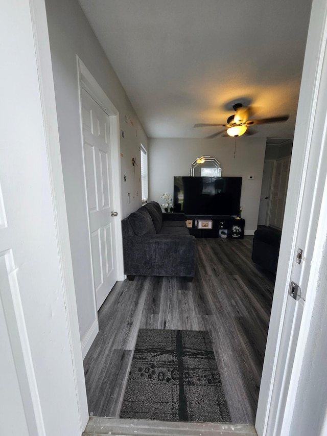 living room with dark wood-type flooring and ceiling fan