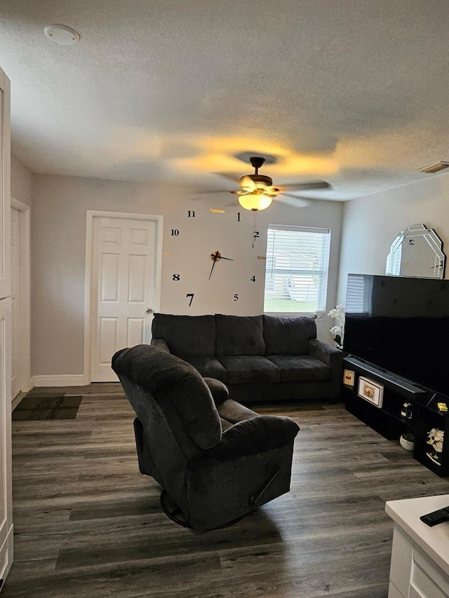 living room featuring ceiling fan, dark wood-type flooring, and a textured ceiling