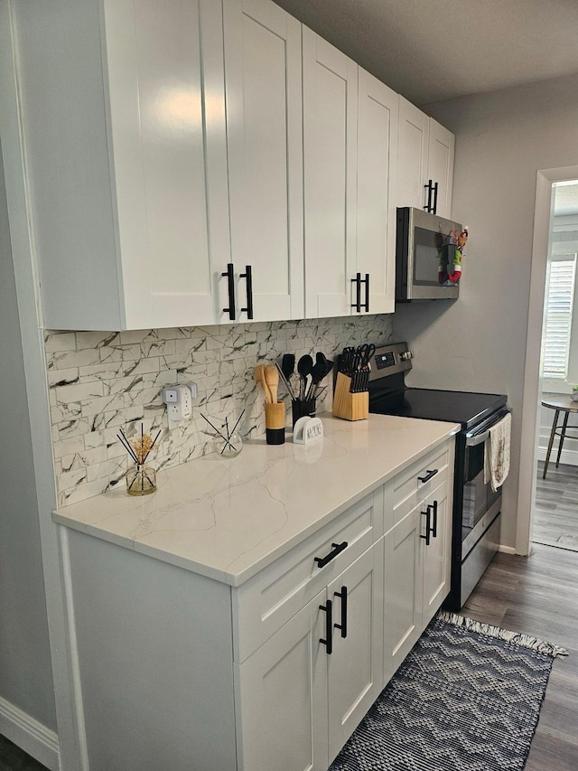 kitchen with stainless steel appliances, light stone countertops, and white cabinets