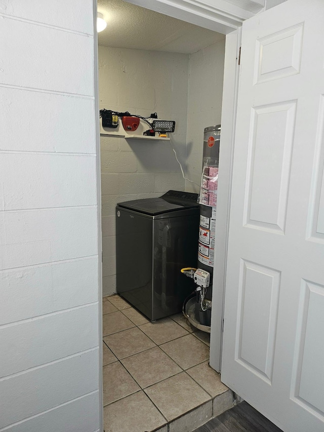 clothes washing area with gas water heater and tile patterned floors