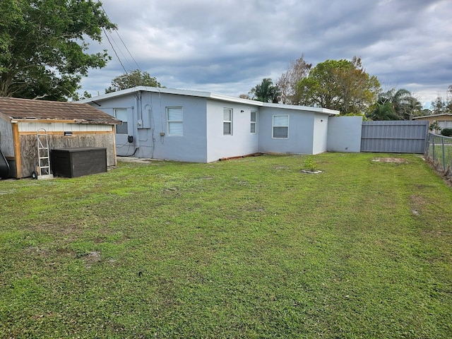 back of house featuring a lawn and a storage unit