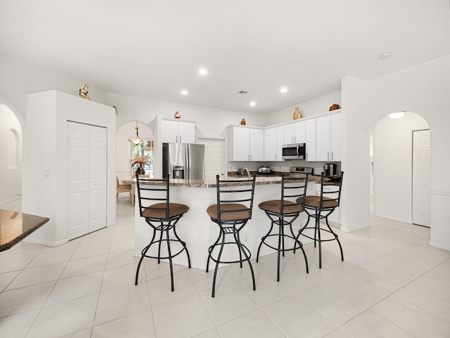 kitchen with white cabinetry, an island with sink, appliances with stainless steel finishes, and a breakfast bar