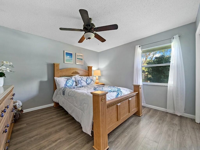 bedroom with ceiling fan, a textured ceiling, and dark hardwood / wood-style flooring