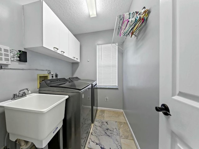 washroom featuring cabinets, sink, washing machine and dryer, and a textured ceiling