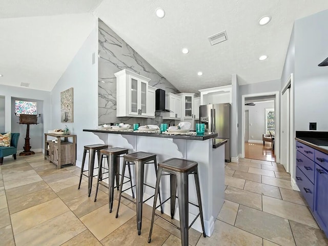 kitchen featuring blue cabinetry, a kitchen breakfast bar, stainless steel refrigerator with ice dispenser, white cabinets, and kitchen peninsula