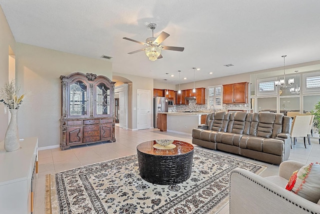 tiled living room featuring ceiling fan with notable chandelier