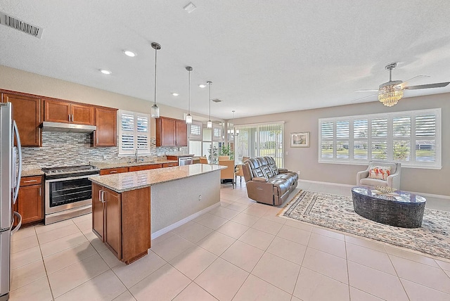 kitchen with hanging light fixtures, a center island, light tile patterned floors, stainless steel appliances, and light stone countertops