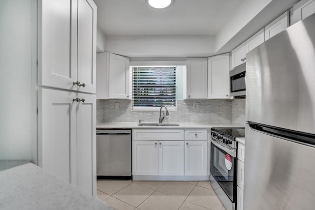 kitchen featuring stainless steel appliances, a sink, light tile patterned flooring, light countertops, and white cabinets