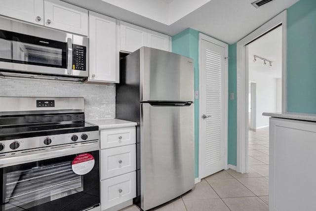 kitchen featuring stainless steel appliances, light tile patterned floors, white cabinets, light countertops, and backsplash