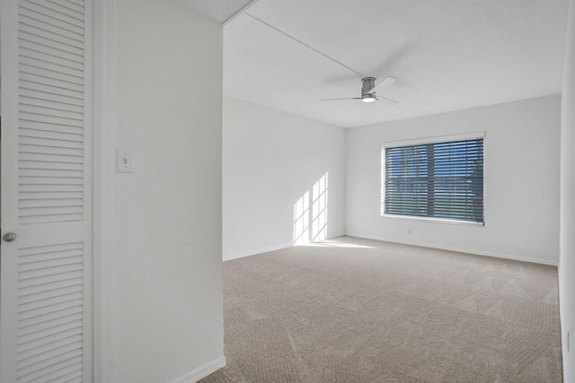 spare room featuring ceiling fan, carpet floors, and baseboards
