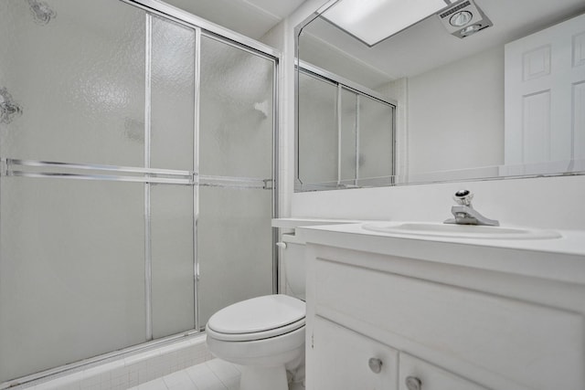bathroom with a shower stall, toilet, vanity, and tile patterned floors