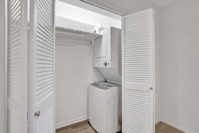 laundry room with estacked washer and dryer, baseboards, and light wood-style flooring