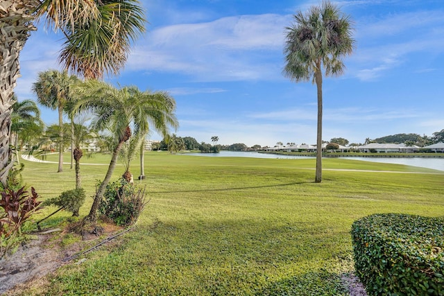 view of home's community with a water view, a lawn, and golf course view
