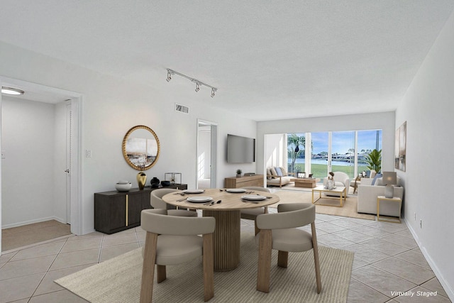 dining space featuring light tile patterned flooring, track lighting, and a textured ceiling