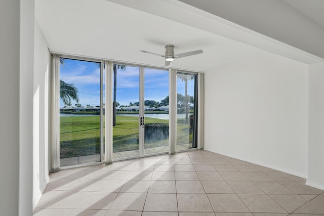 tiled empty room featuring floor to ceiling windows, ceiling fan, and a water view